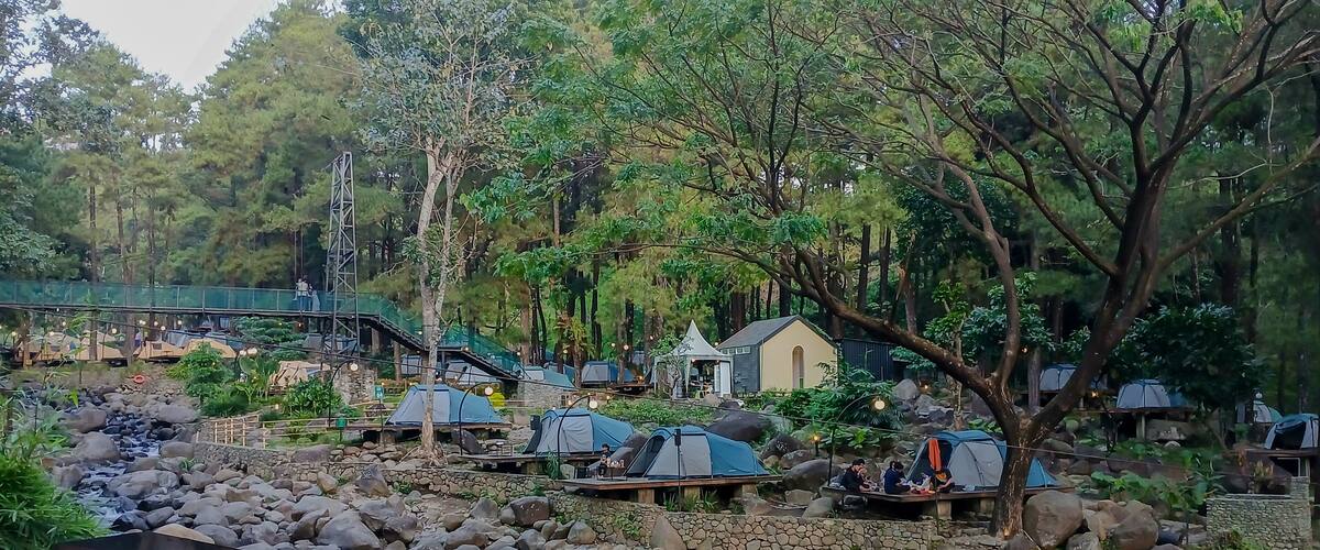 A campsite with tents, a small stream, and a bridge.