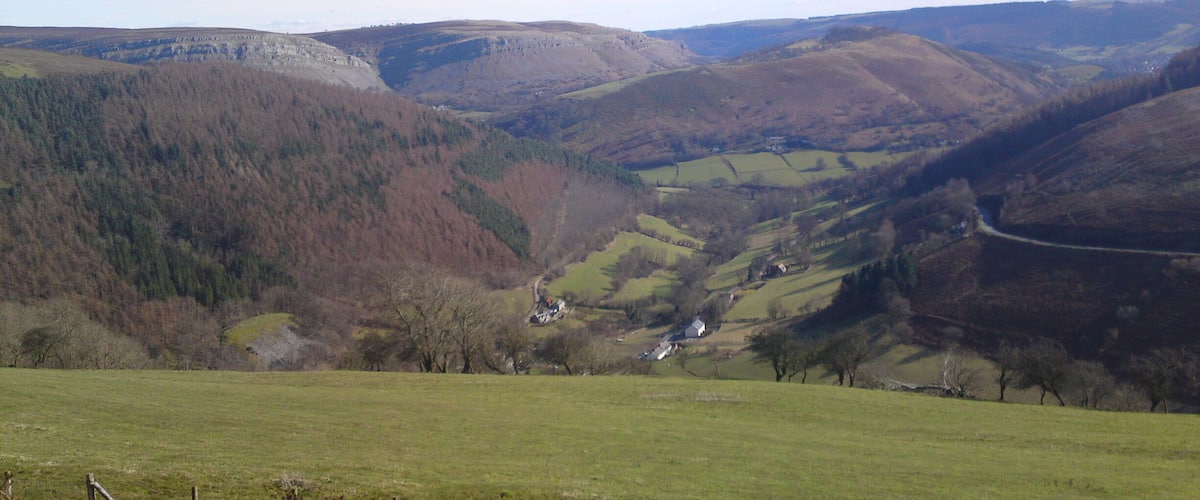 A valley with rolling hills, a winding road, and scattered houses.