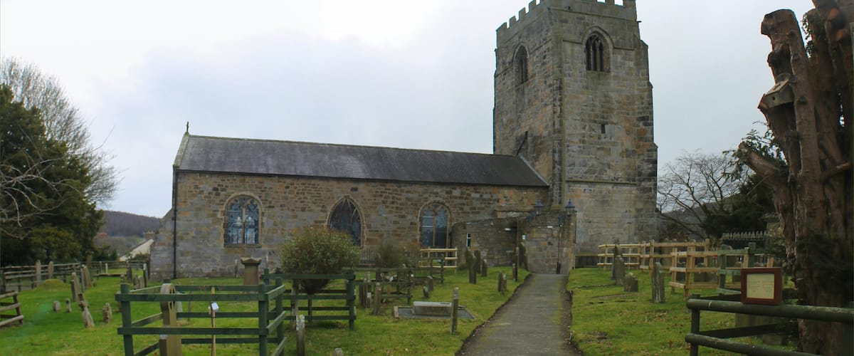 A church with a tall tower and a cemetery in front.