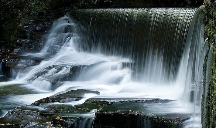 Uma cascata em vários níveis, com água caindo sobre as rochas.