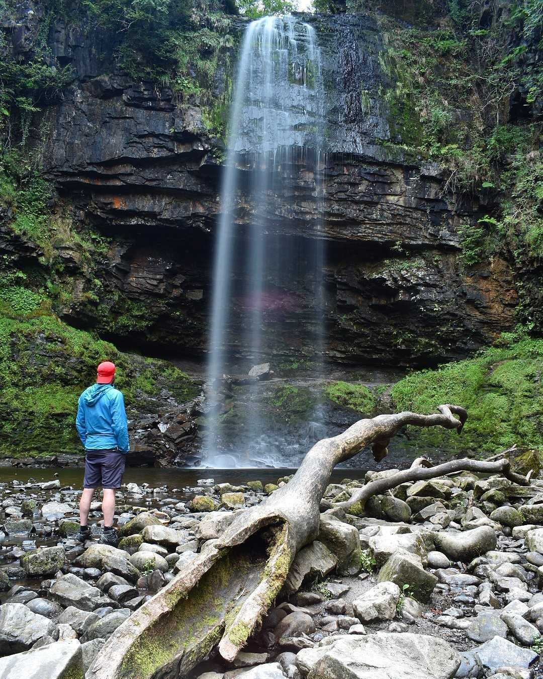 A waterfall cascading down a rocky cliff surrounded by greenery.