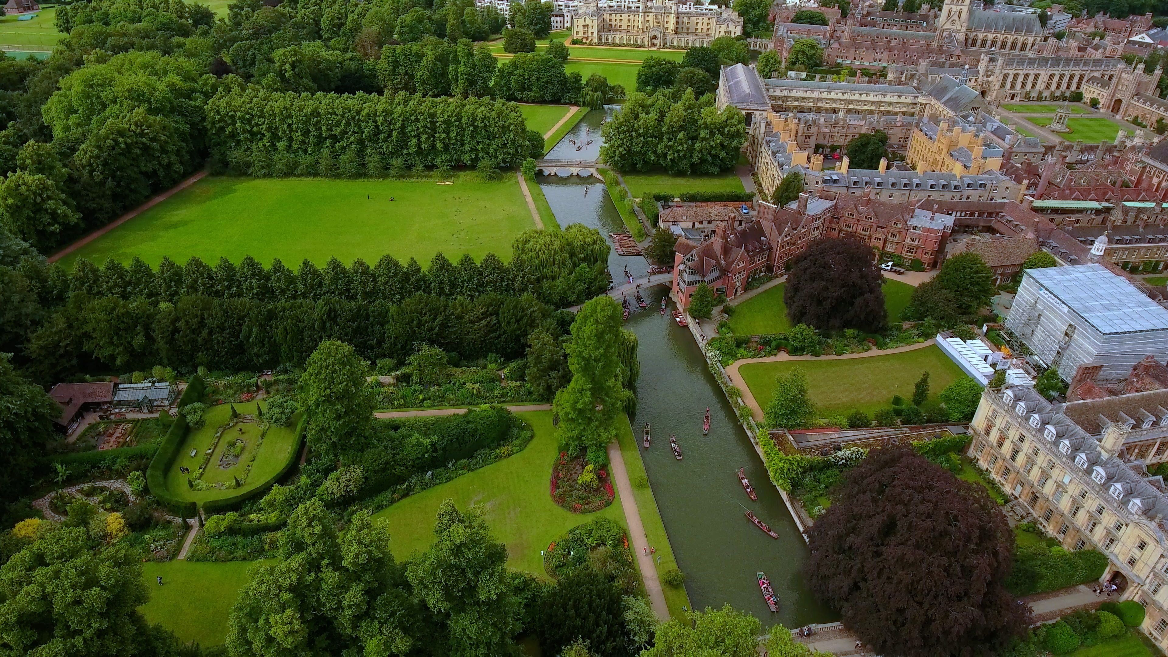 An aerial view of a university campus with a river, green lawns, and historic buildings.