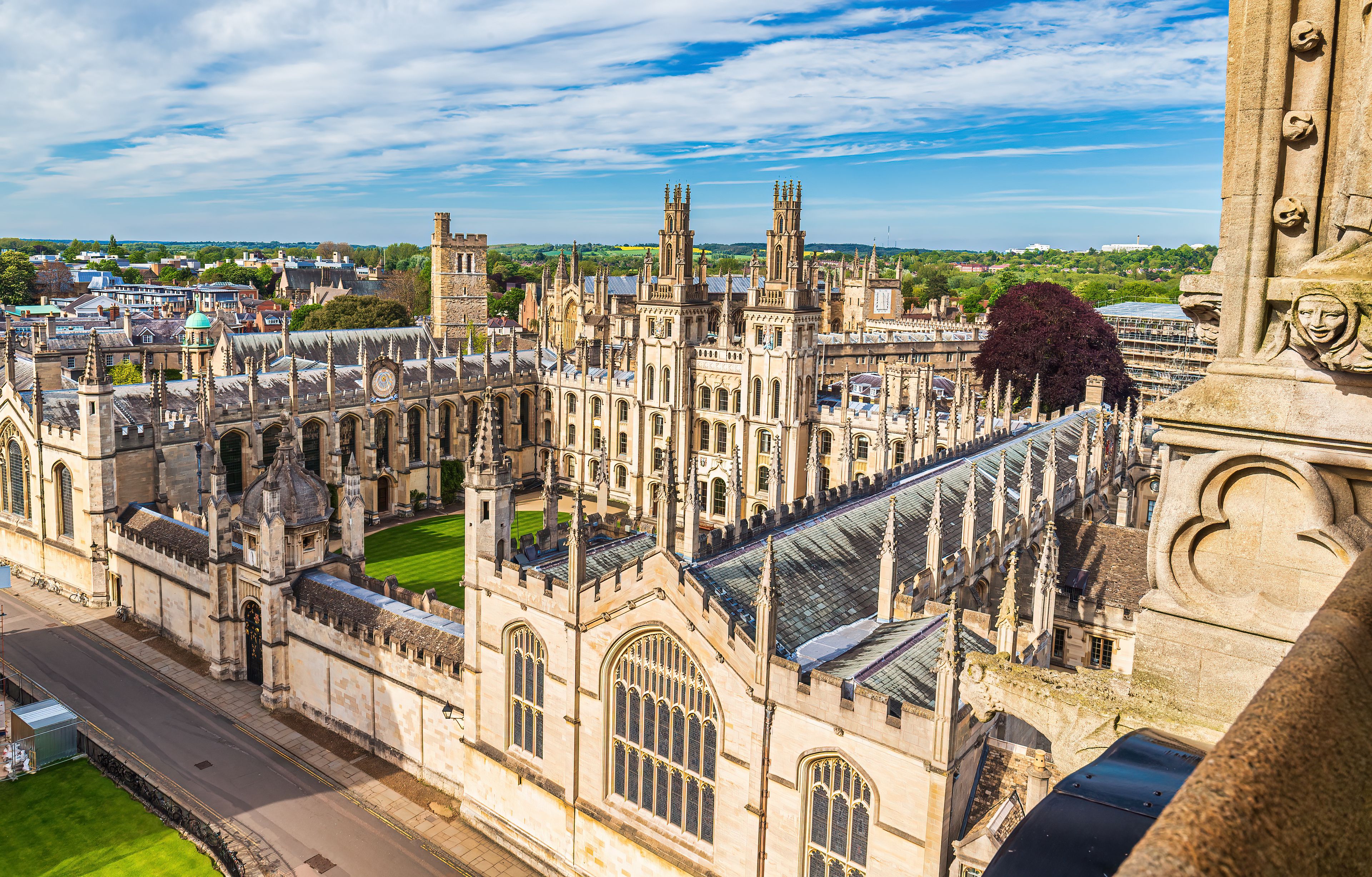 A historic university campus with Gothic architecture, including a prominent clock tower and intricate stonework.