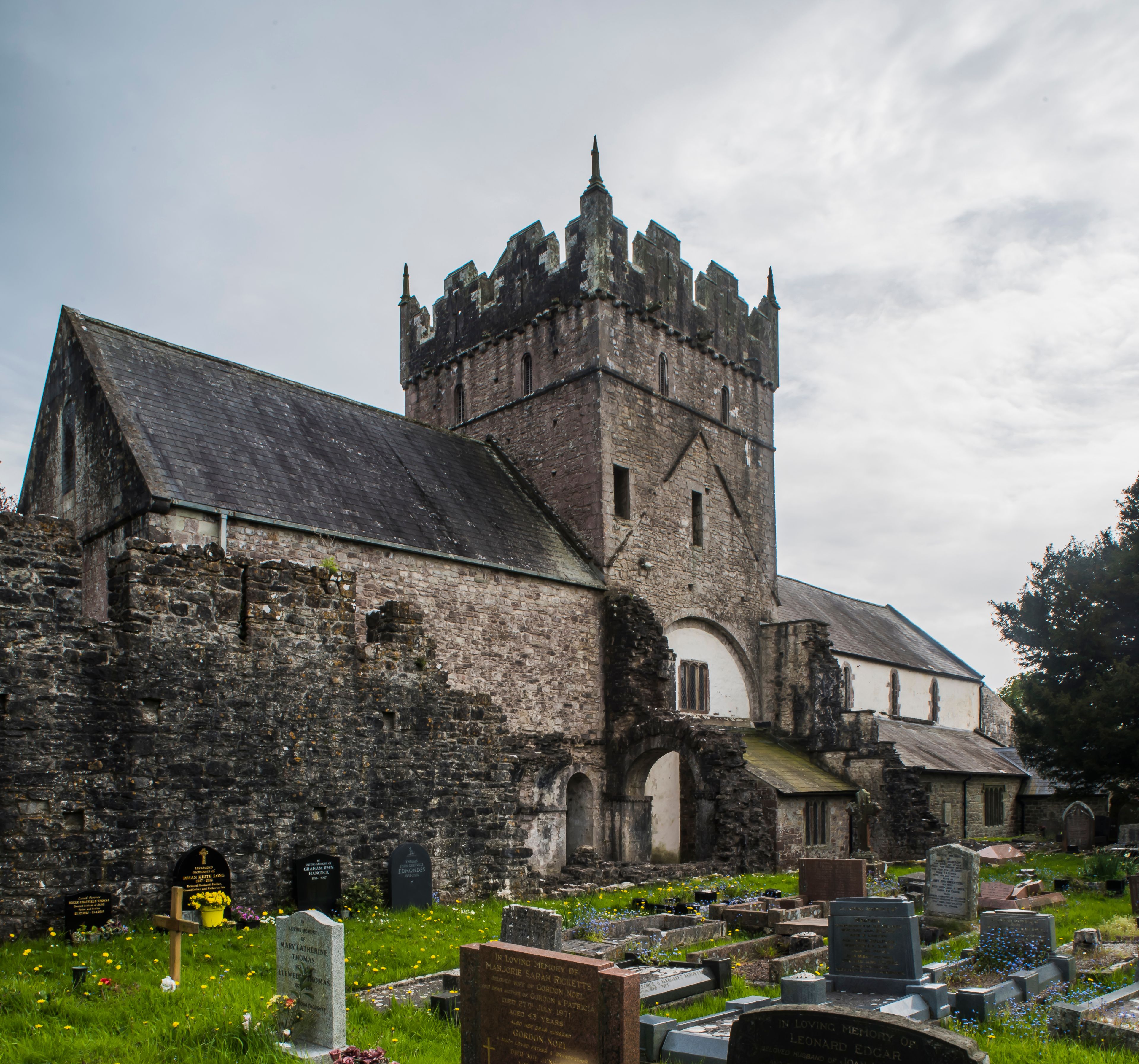 Una iglesia histórica con una alta torre y un cementerio frente a ella.