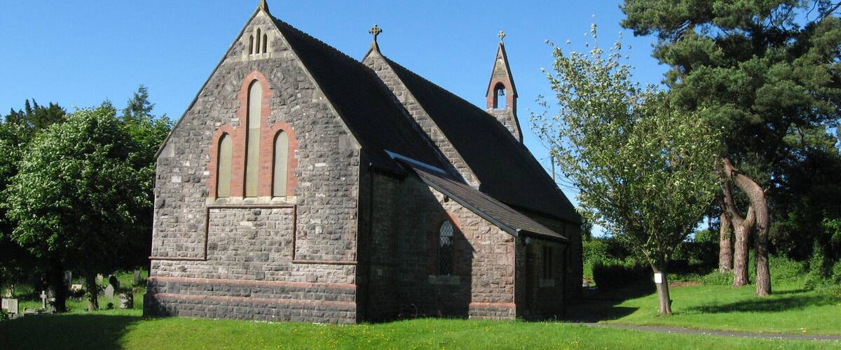 A stone church with a pointed roof and a bell tower.