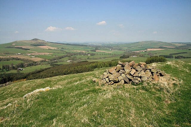 The summit of Bonchester Hill A small cairn marks the 323m summit of this prominent little hill overlooking the village of Bonchester Bridge. The summit is also the site of a fort and settlement. The hill on the far left is Rubers Law with Black Law on the far right.