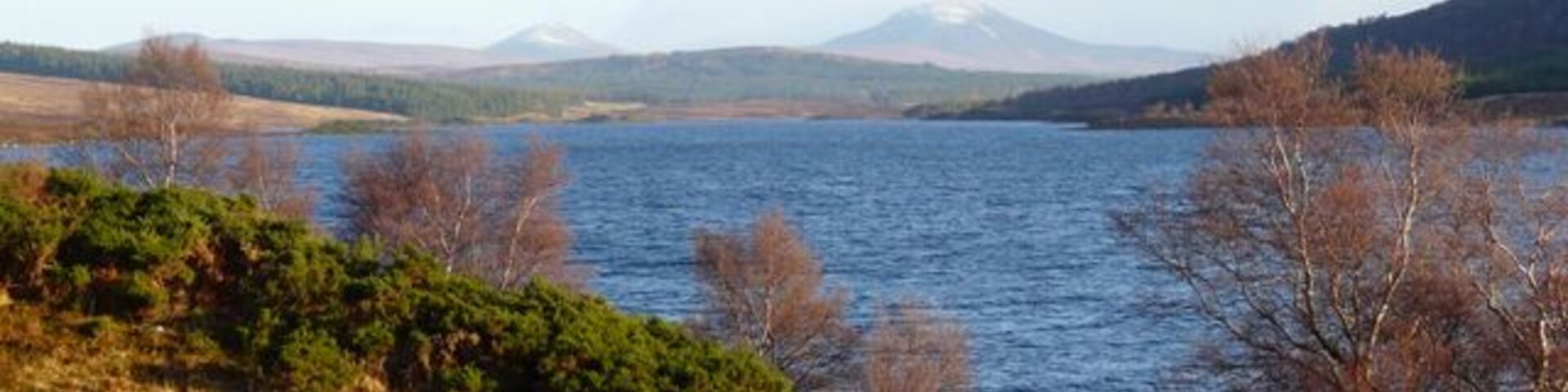 Un lago rodeado de colinas y vegetación escasa.