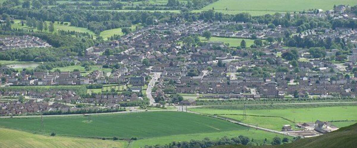 A town with a river, green fields, and scattered houses.