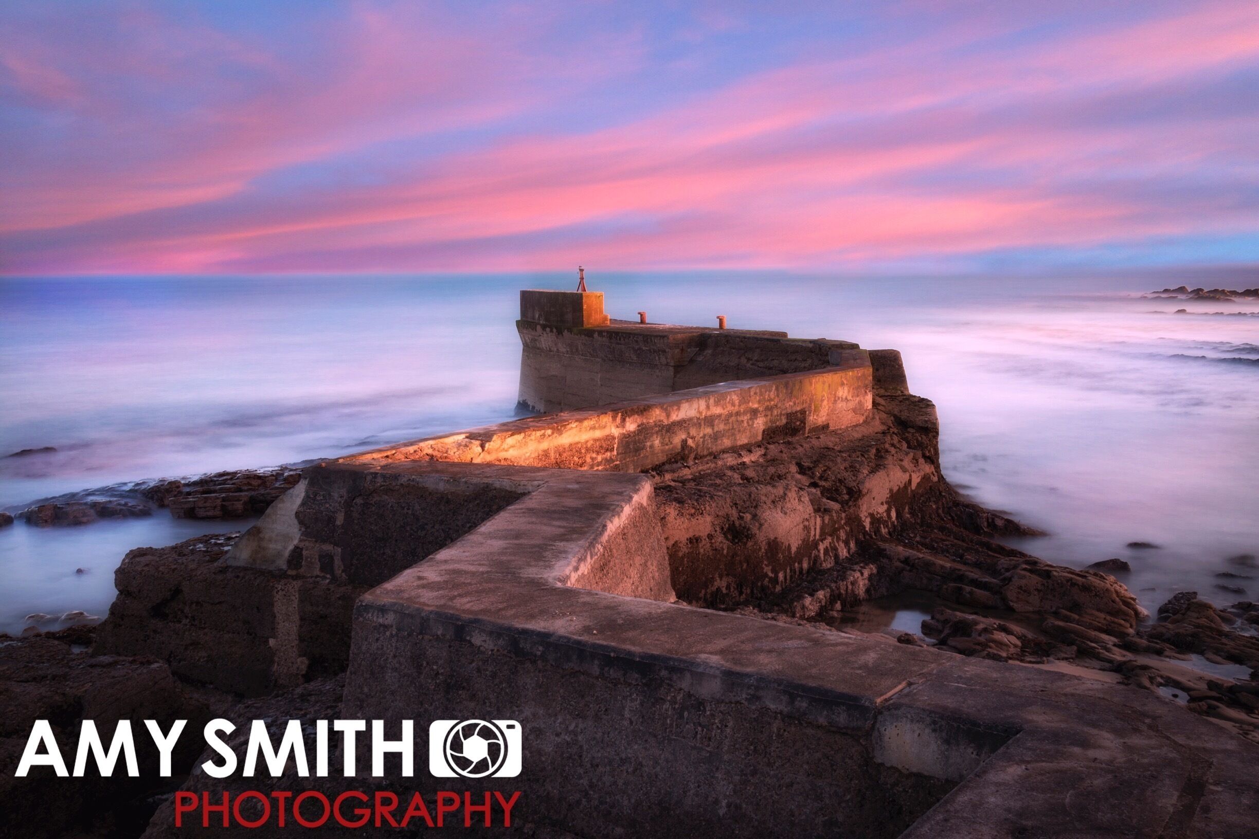 A coastal structure with a sunset sky.