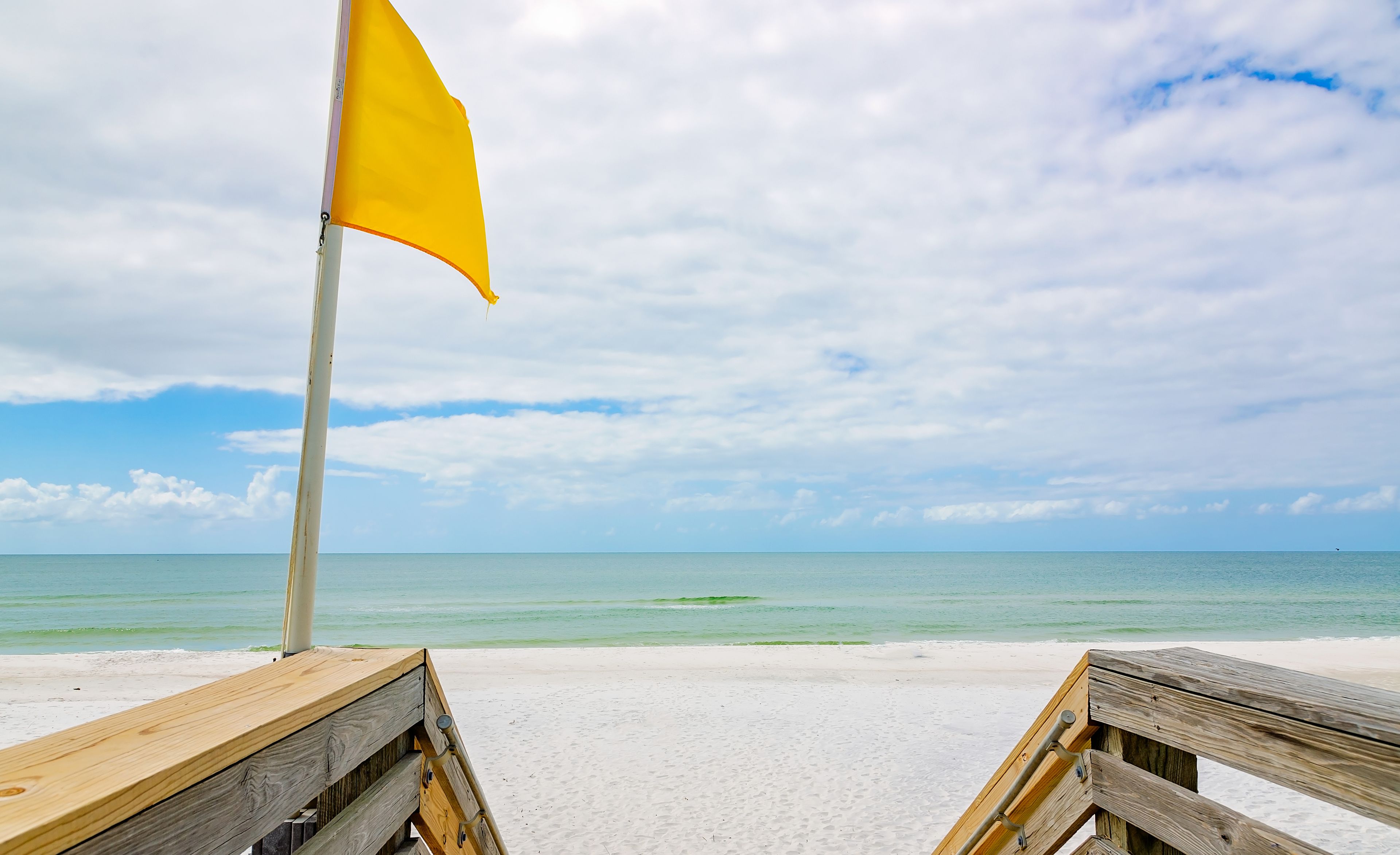 A beach with wooden benches and a yellow flag.