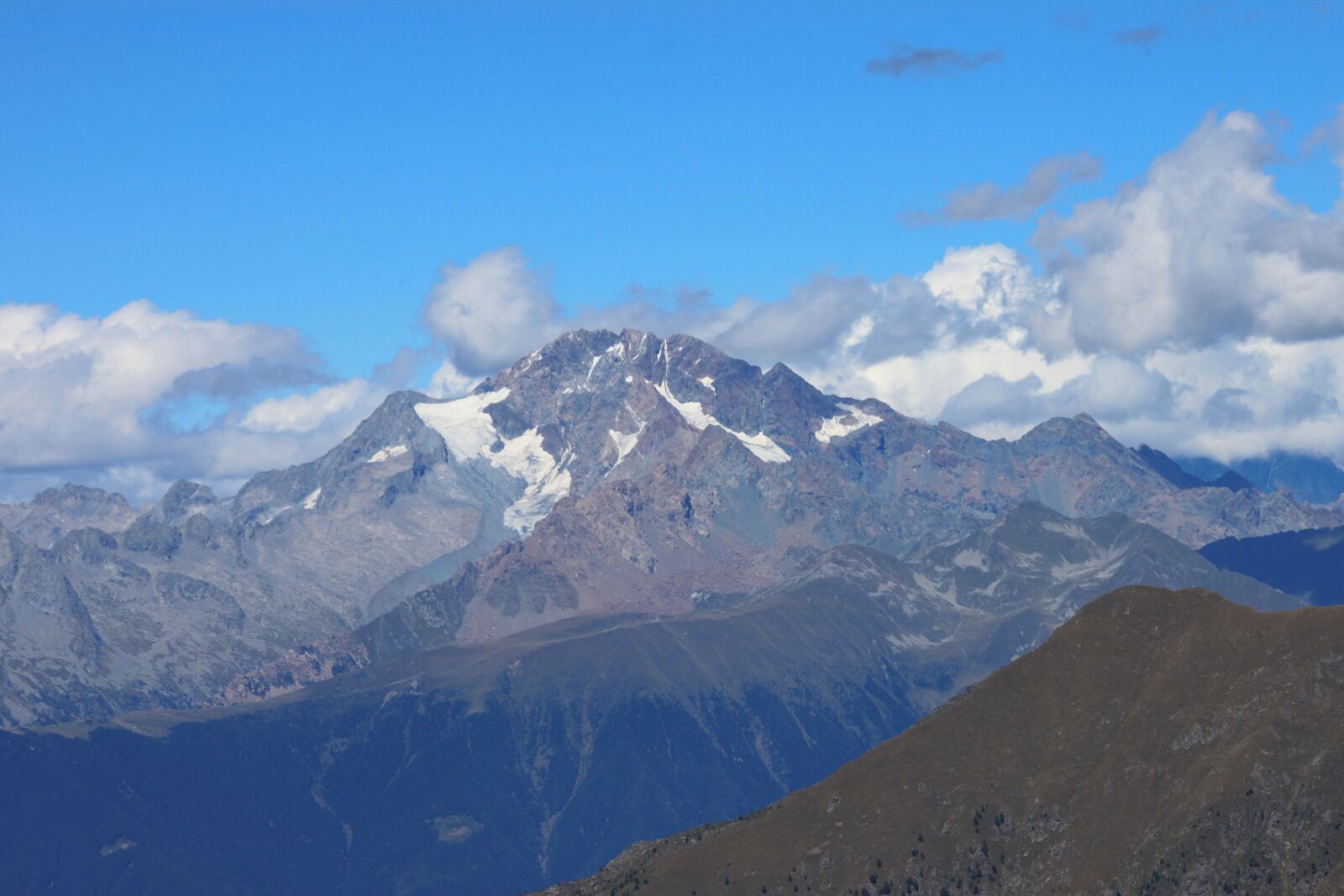A mountain range with snow-capped peaks and a clear blue sky.