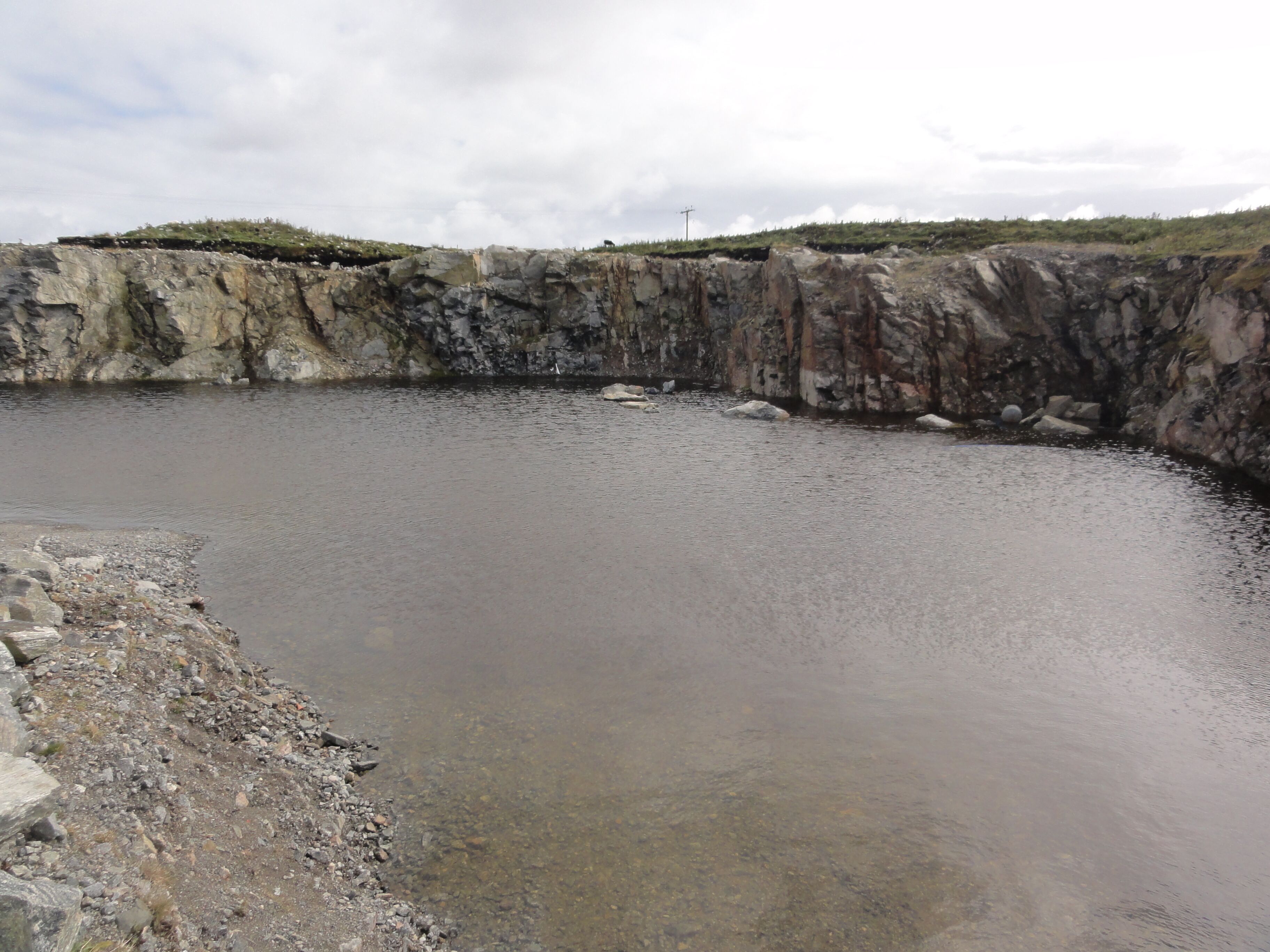 A large, circular pond surrounded by rocky terrain and sparse vegetation.
