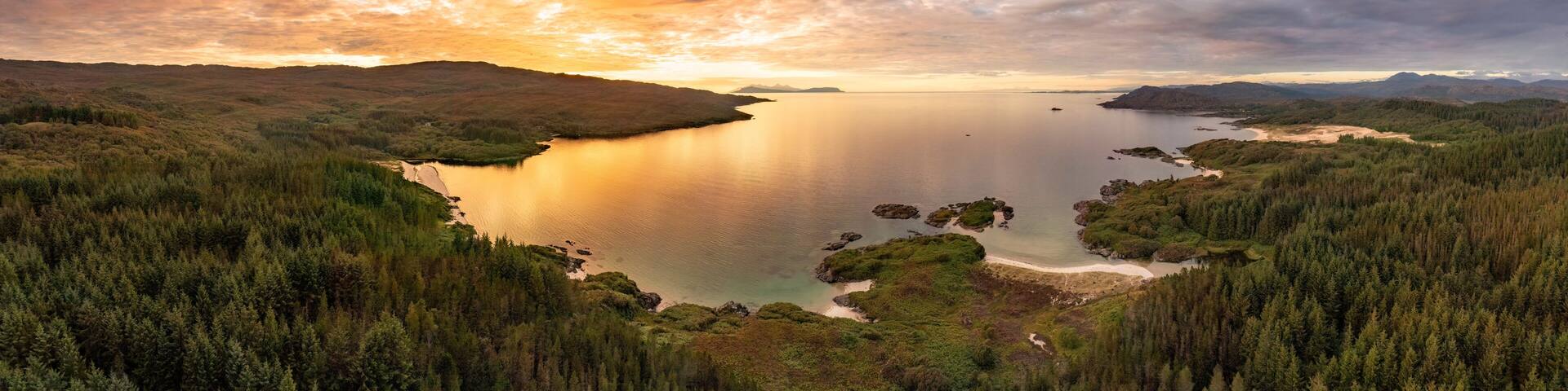Aerial view of Singing sands and Cul na Croise beach with Eigg and Rum at sunset, Scotland