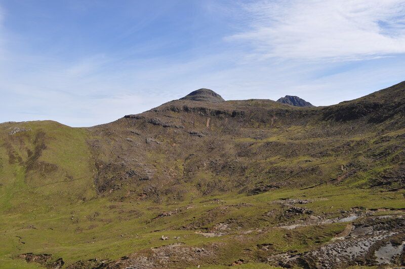 A mountainous landscape with grassy slopes and rocky terrain.