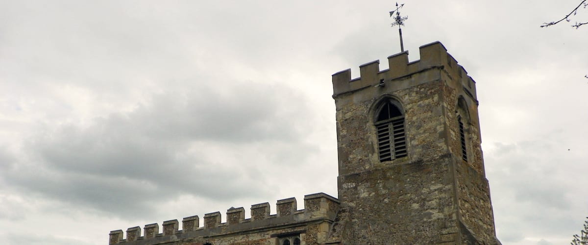 A historic stone church with a tall bell tower and arched windows.