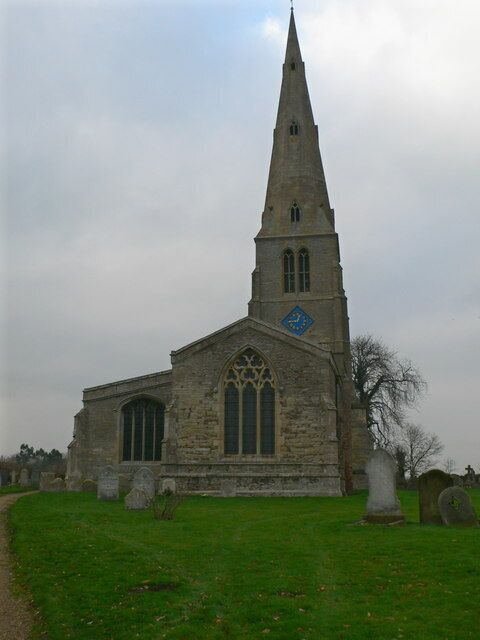 A stone church with a tall spire and a blue emblem on the tower.