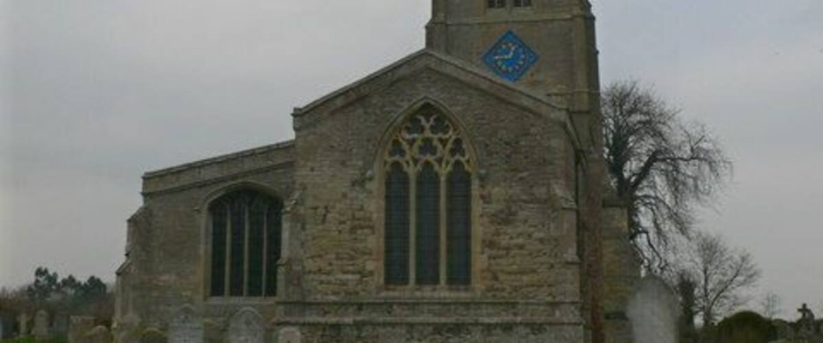 A stone church with a tall spire and a blue emblem on the tower.