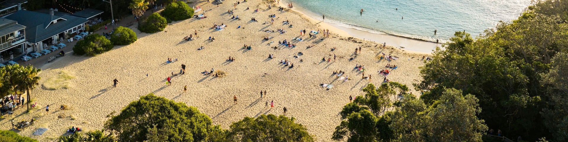 A coastal town with a sandy beach, a pier, and residential buildings.
