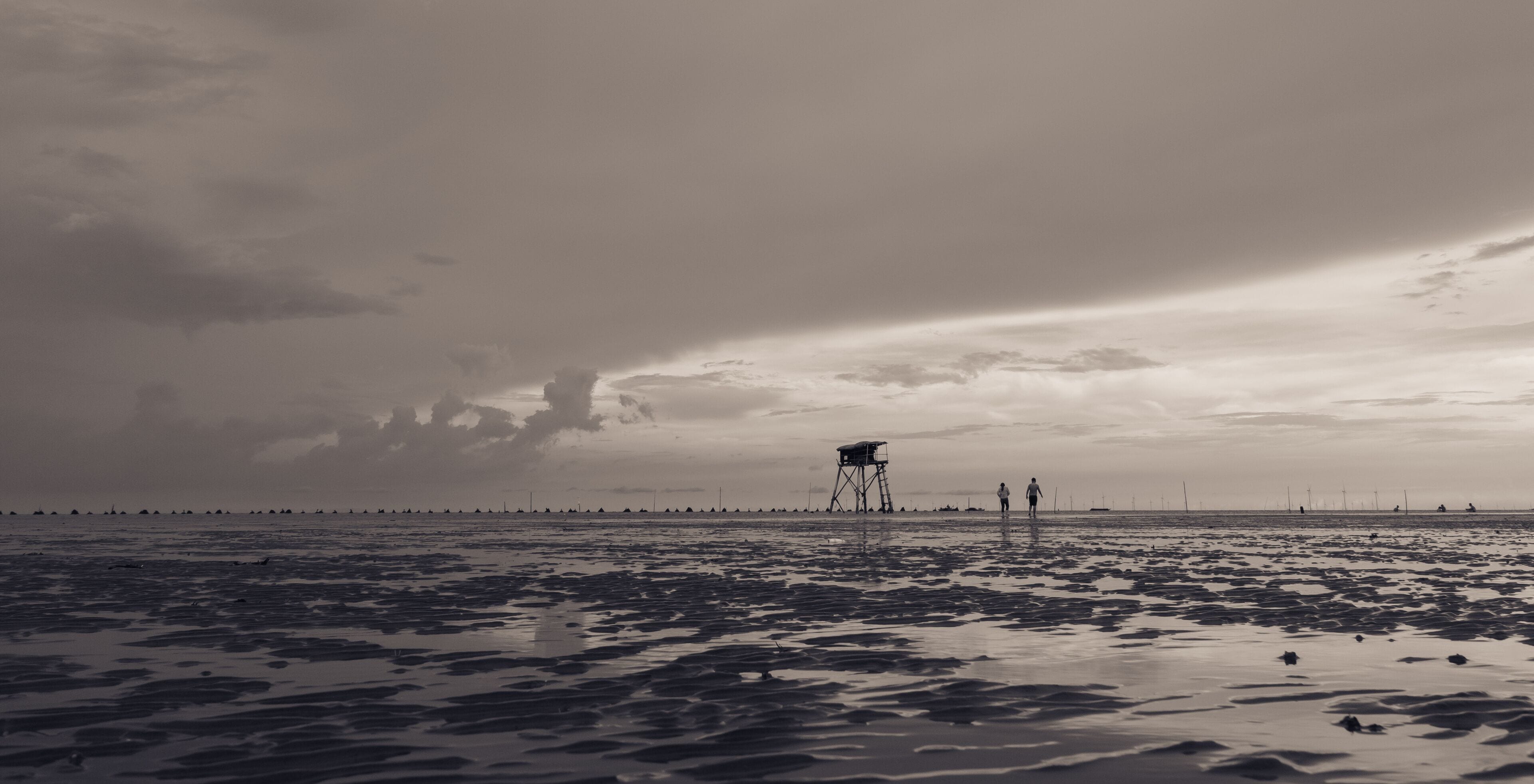A beach with a lifeguard tower and people walking.