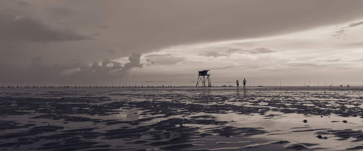 A beach with a lifeguard tower and people walking.