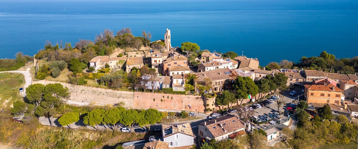 A coastal village with a prominent church tower, terraced houses, and a clear view of the sea.