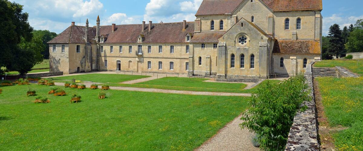 A large historic building with a courtyard, surrounded by greenery and a clear sky.