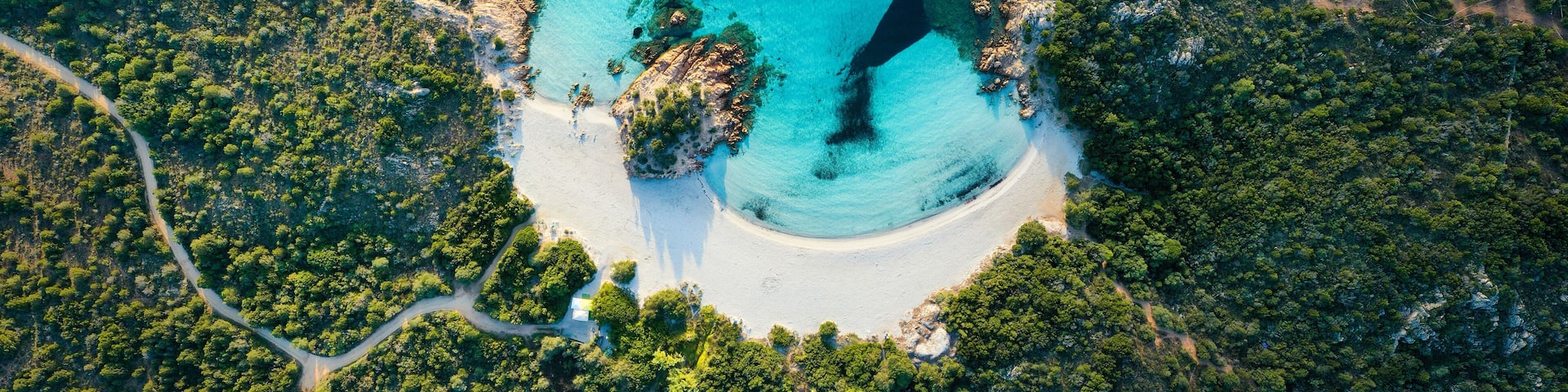 View from above, stunning aerial view of a green coast with the beautiful Prince Beach (Spiaggia del Principe) a white sand beach bathed by a turquoise water. Sardinia, Italy.