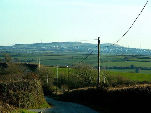 A rural road with a clear view of rolling hills and distant power lines.