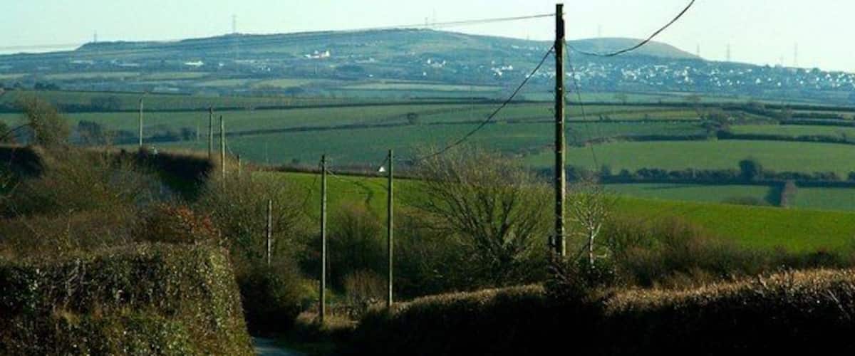 A rural road with a clear view of rolling hills and distant power lines.