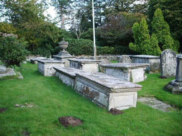 A cemetery with stone headstones and a central urn monument.
