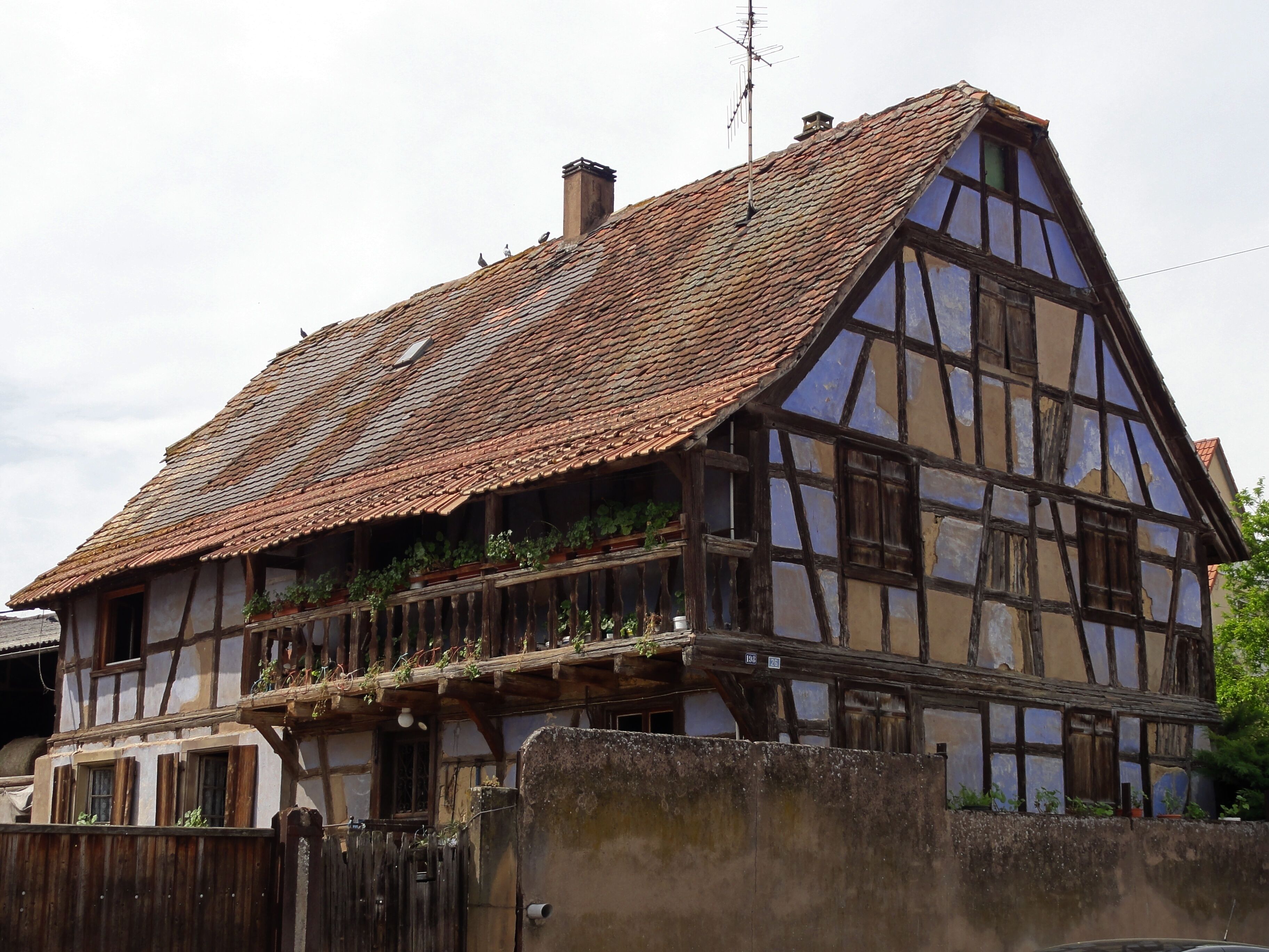 A traditional half-timbered house with a steeply pitched roof and a wooden balcony.