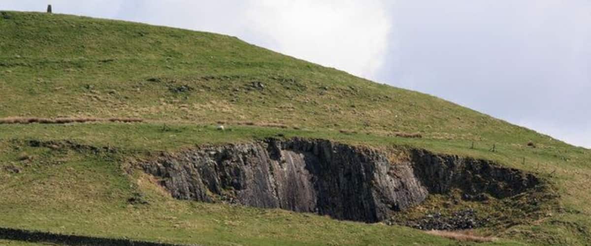 A grassy hill with a deep sinkhole.