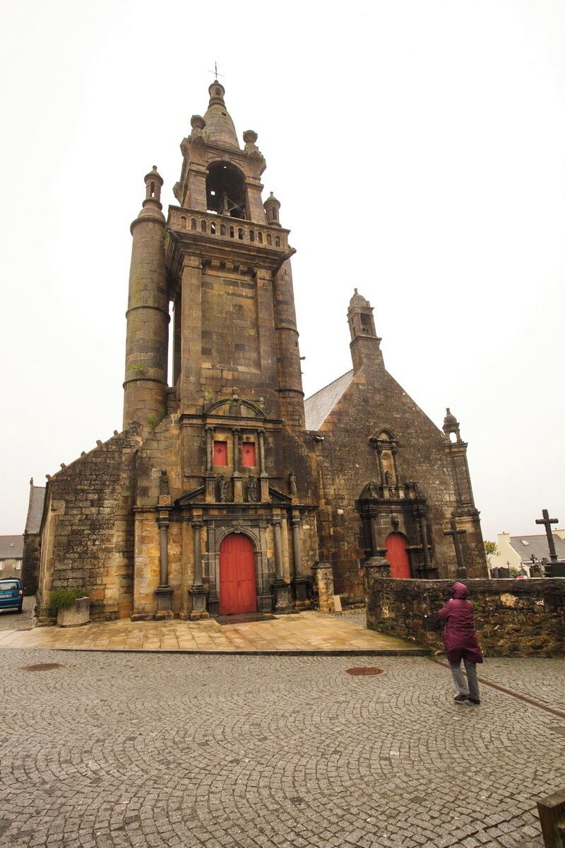 An old stone church with a tall bell tower and a red door.