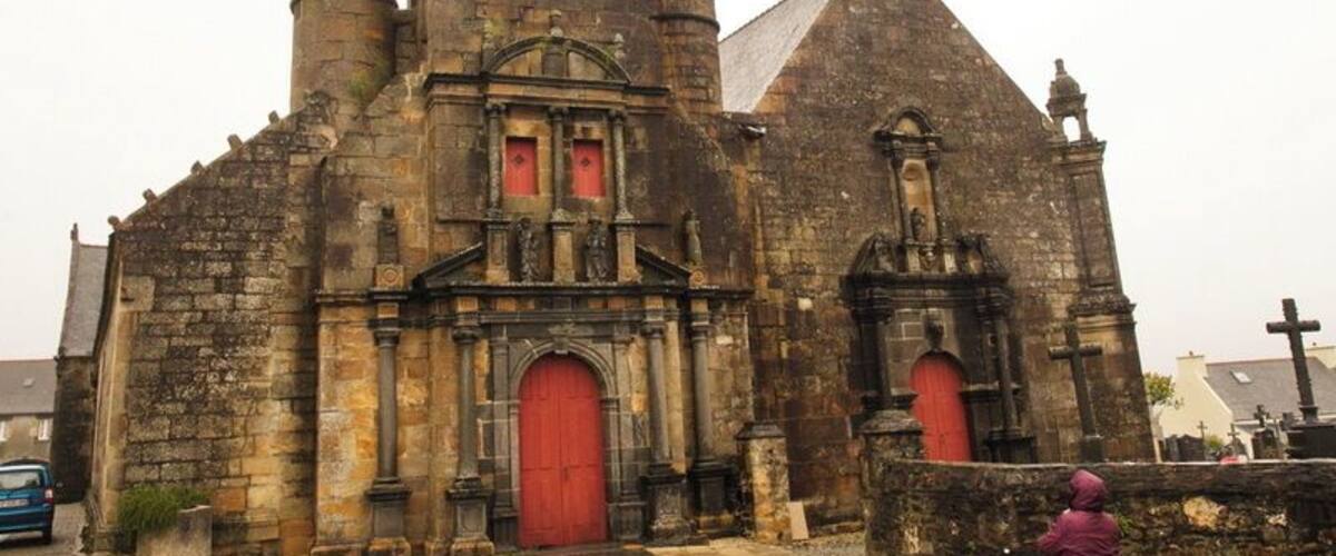 An old stone church with a tall bell tower and a red door.