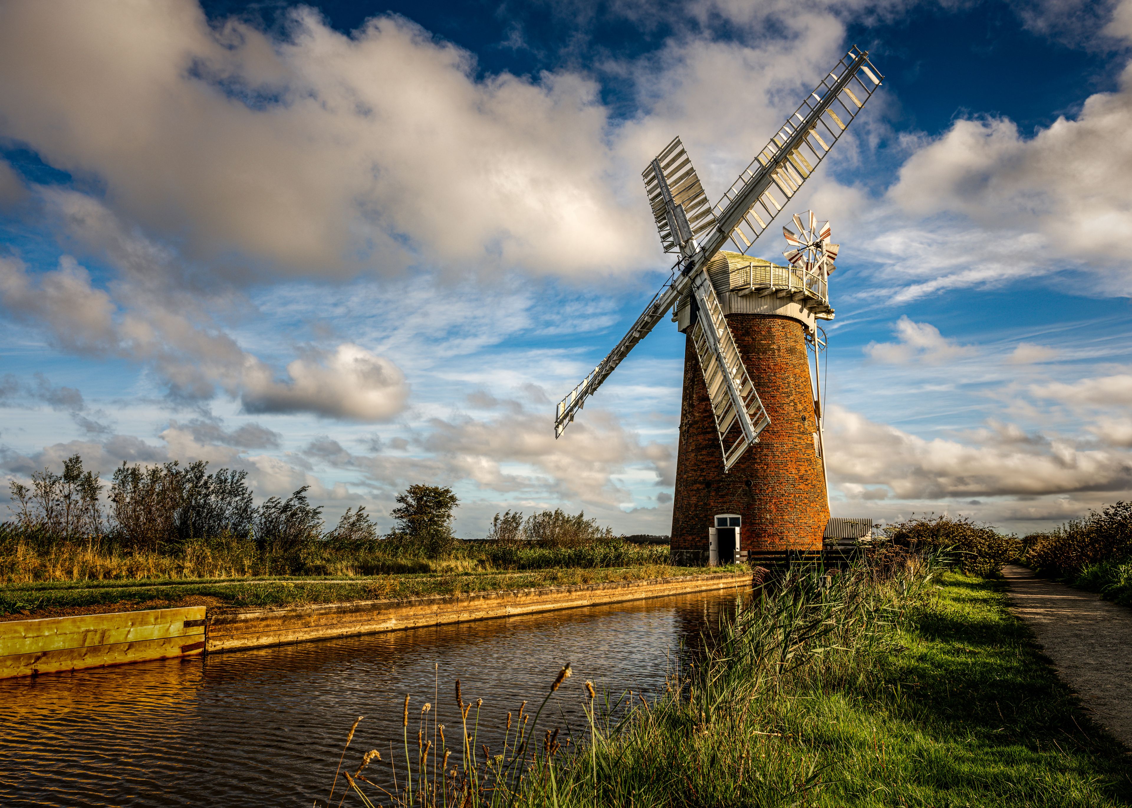Horsey Windpump beside Norfolk Broads waterway beneath a dramatic autumn sky