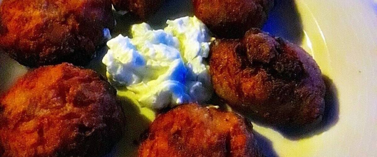 A plate of fried food with a dollop of sour cream.