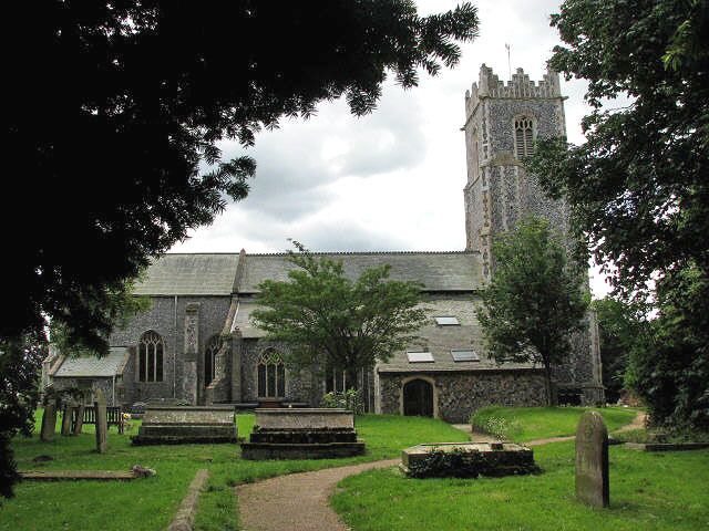 A historic church with a tall tower, surrounded by a cemetery with headstones and a pathway.