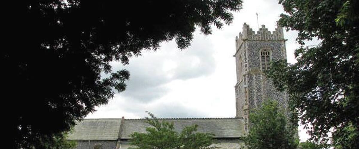 A historic church with a tall tower, surrounded by a cemetery with headstones and a pathway.