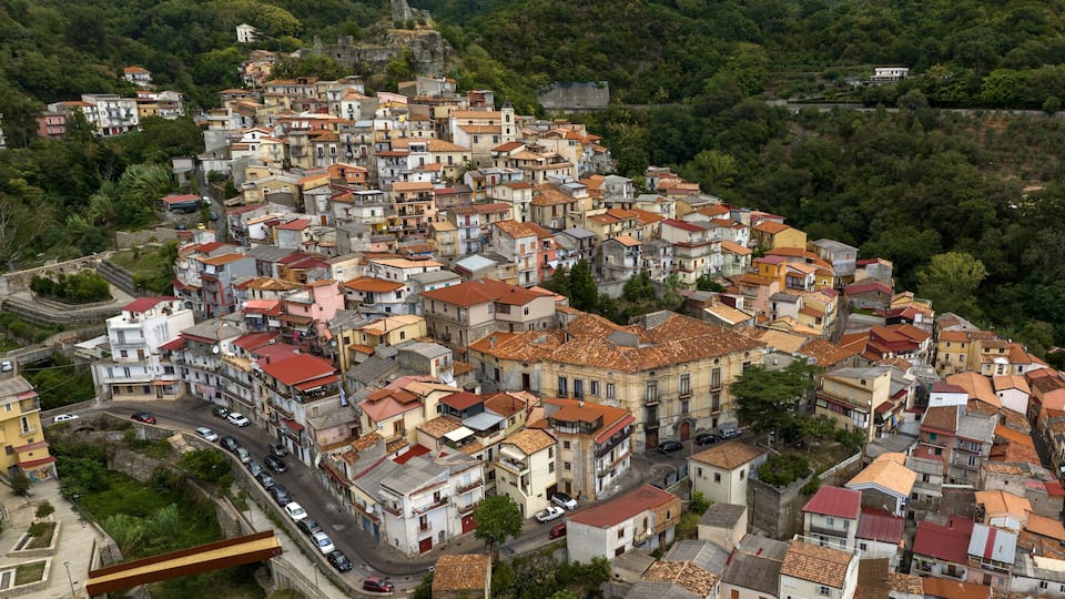 A densely packed hillside town with terracotta-roofed buildings and narrow streets.