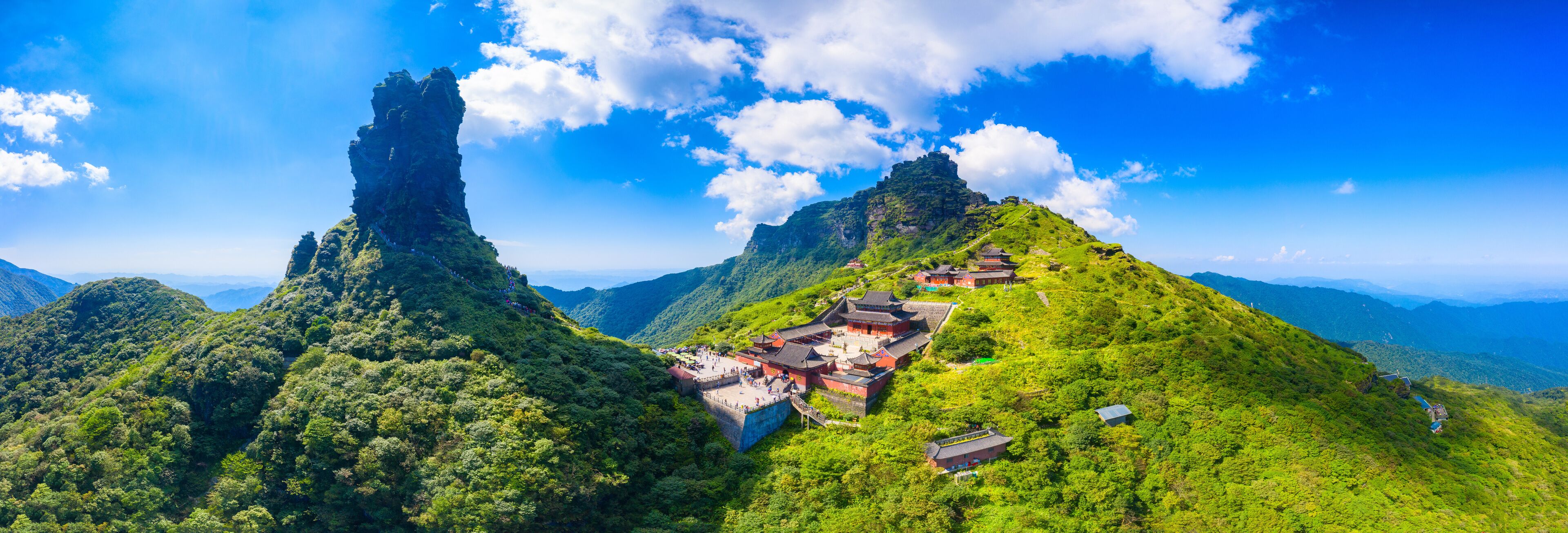 A mountainous landscape with traditional architecture and a prominent rock formation.