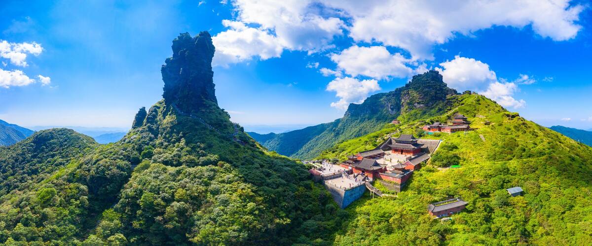 A mountainous landscape with traditional architecture and a prominent rock formation.
