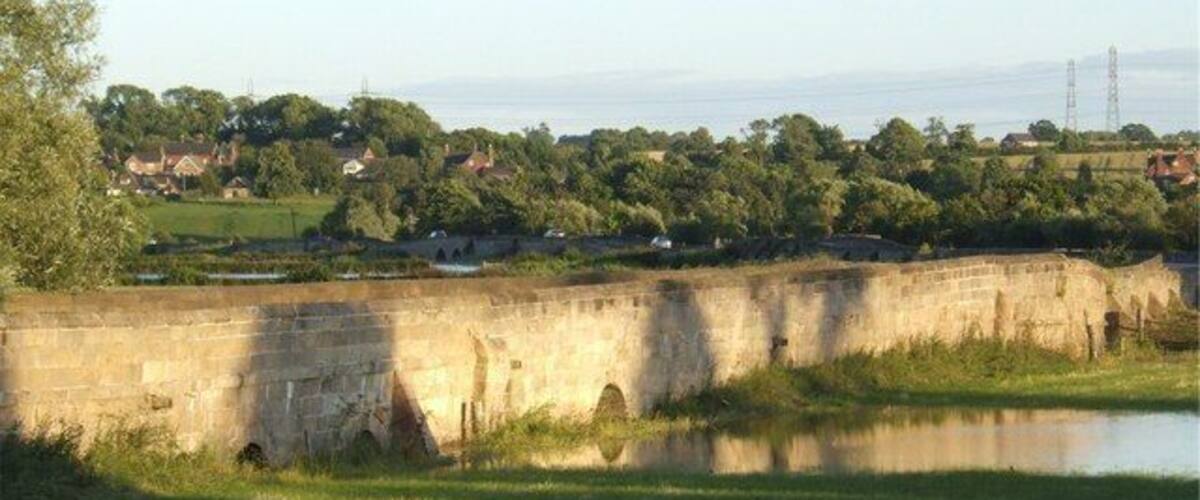 Swarkestone Causeway Swarkestone Causeway is a grade-1 listed structure dating from the 13th century. It was built to cross marshy ground in the flood plain of the River Trent. The name Trent is thought to mean "trespasser", i.e. river liable to flood. The land still floods regularly in bad weather. The river itself is crossed by an 18th century hump-backed bridge, built when this section of the river was navigable.