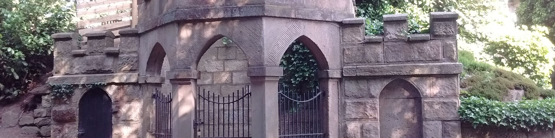 Uma construção imponente, semelhante a um castelo de pedra, com janelas em arco e entrada protegida por grades.