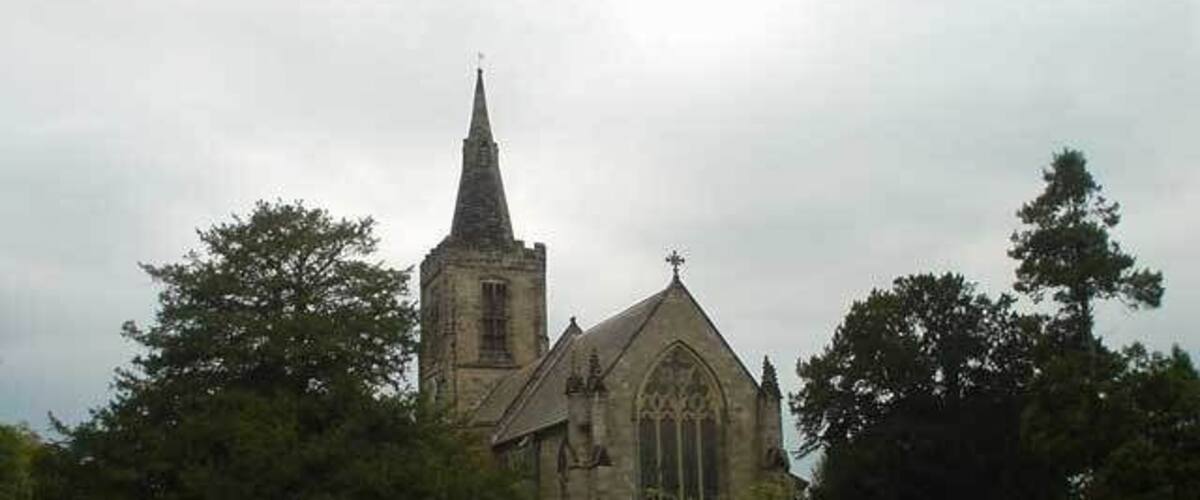 A church with a tall spire and a smaller building with a cross on top.