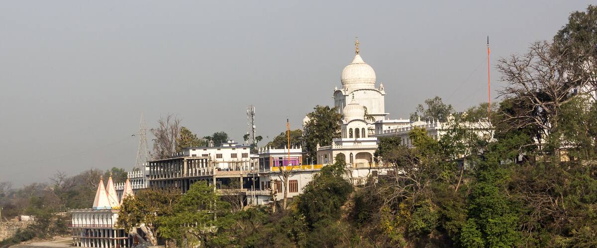 A river with a temple on a hill, surrounded by trees and buildings.