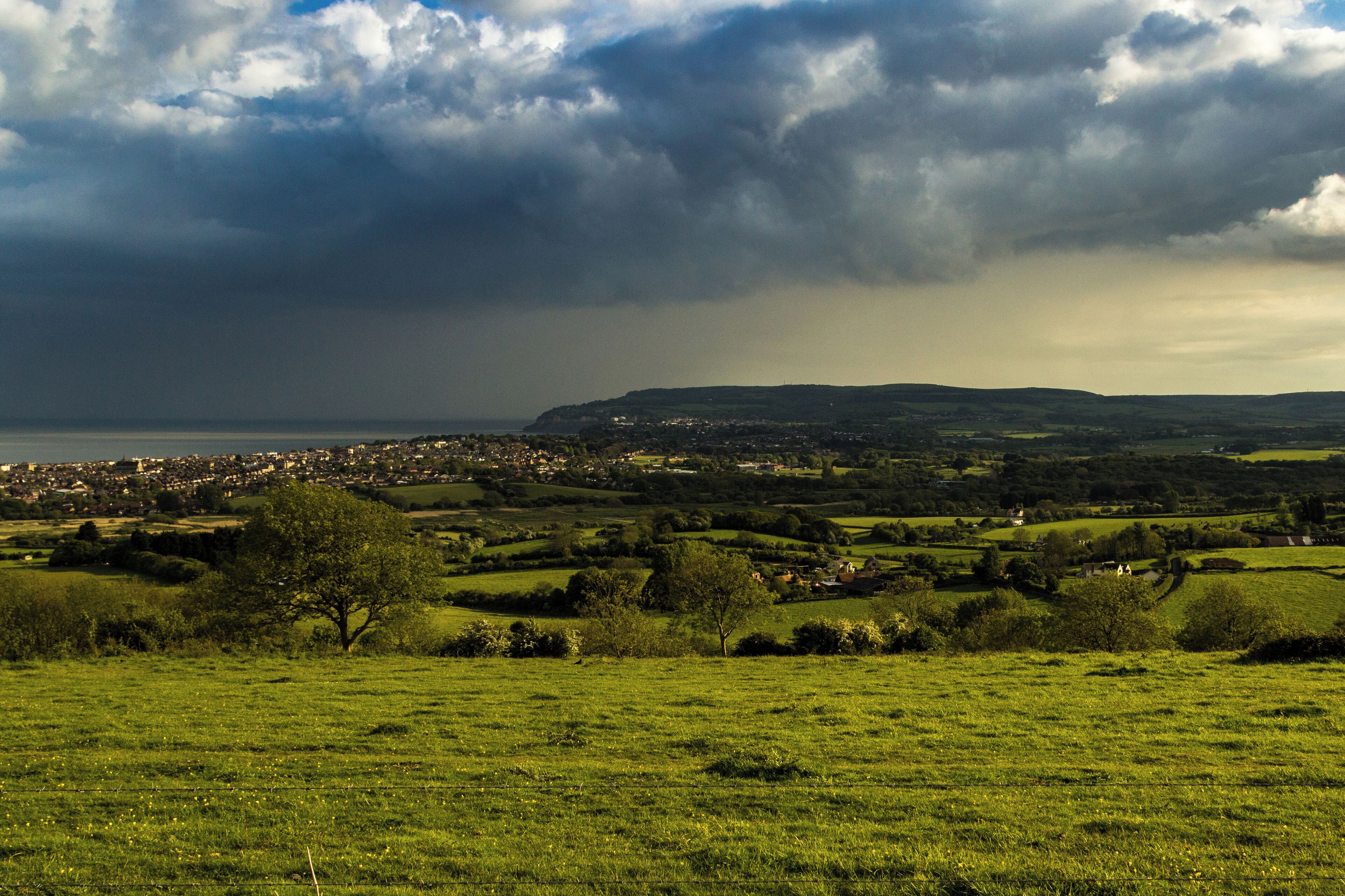A coastal town with rolling hills and a cloudy sky.