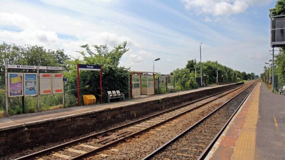 A railway station with multiple tracks, a platform, and information boards.