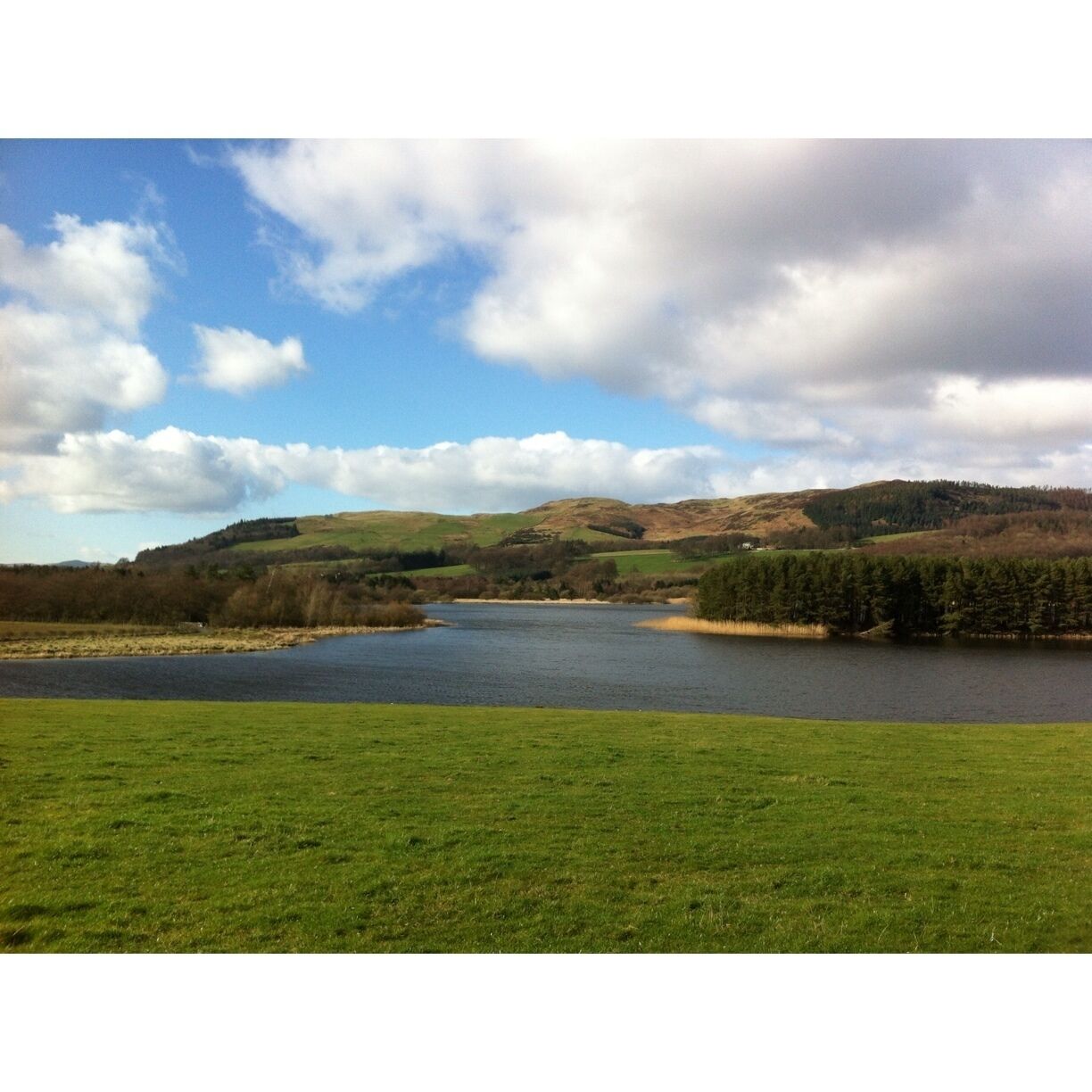 A lake surrounded by green fields and hills.