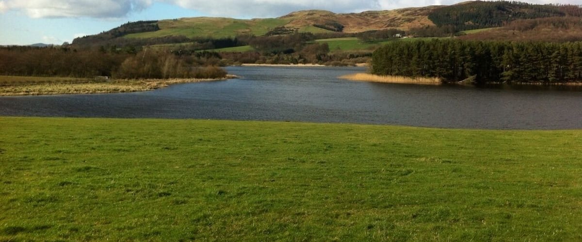 A lake surrounded by green fields and hills.