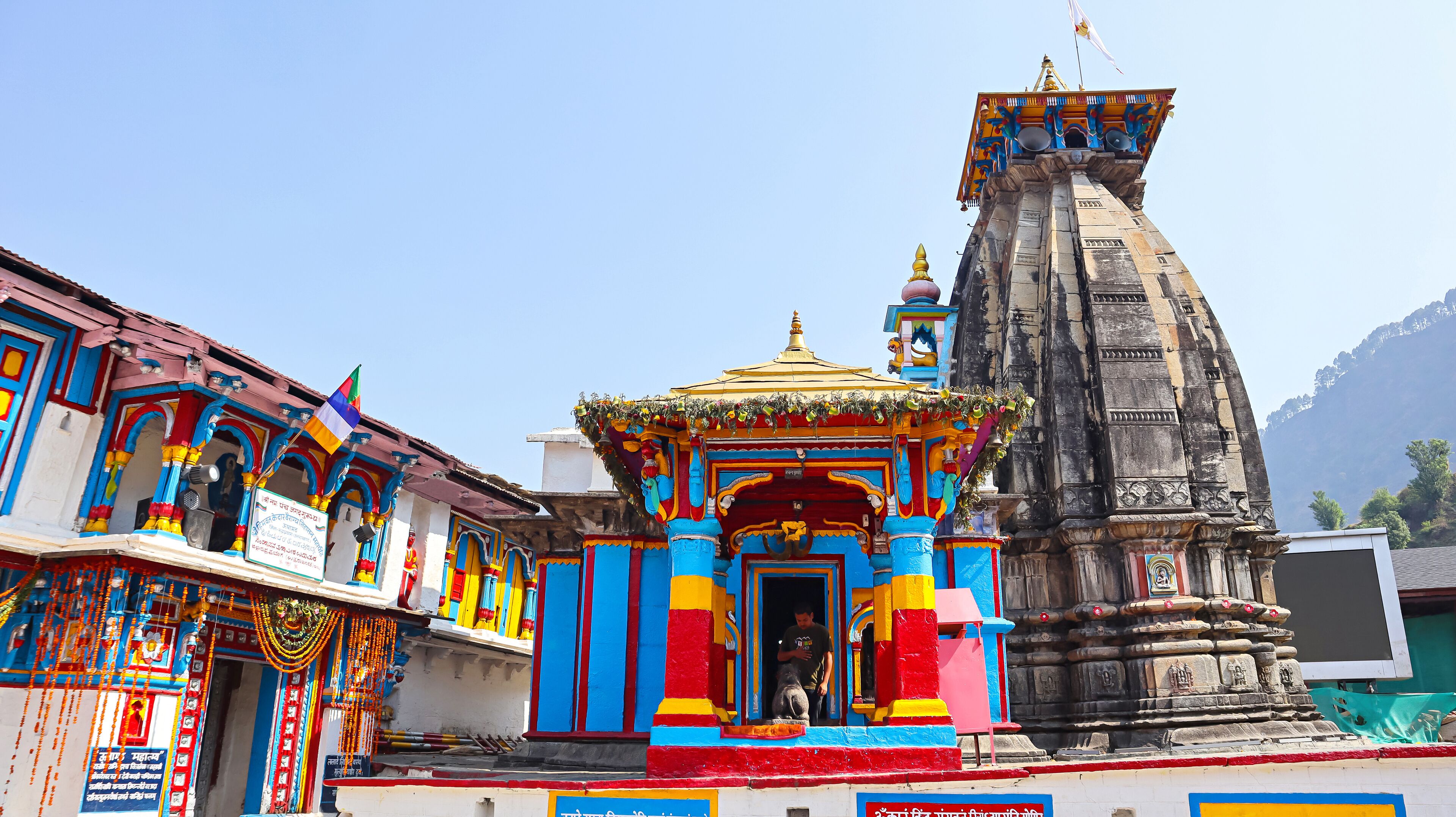 A colorful temple with a golden spire and a stone structure.